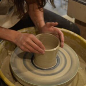 woman spinning clay on pottery wheel