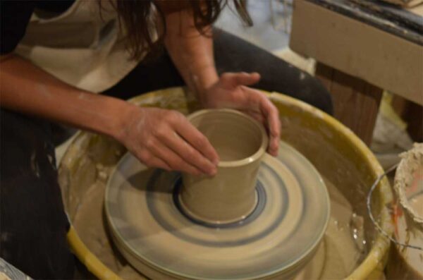 woman spinning clay on pottery wheel